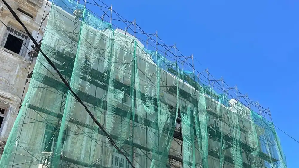 Andaime fachadeiro da SAF com tela de proteção verde cobrindo a fachada de um edifício em obra, Recife